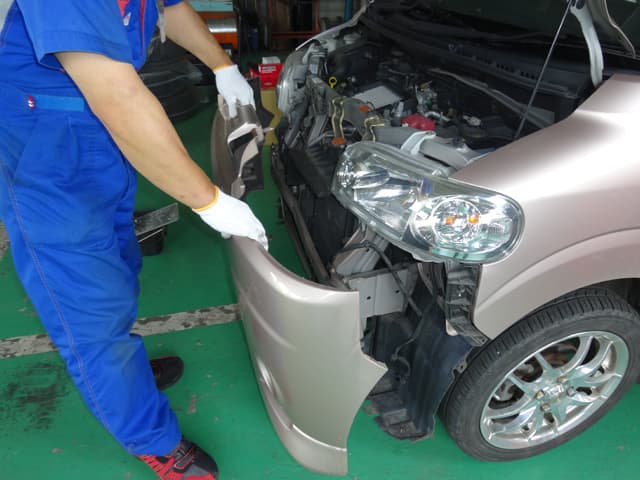 自動車整備士がフロントバンパーを外している風景